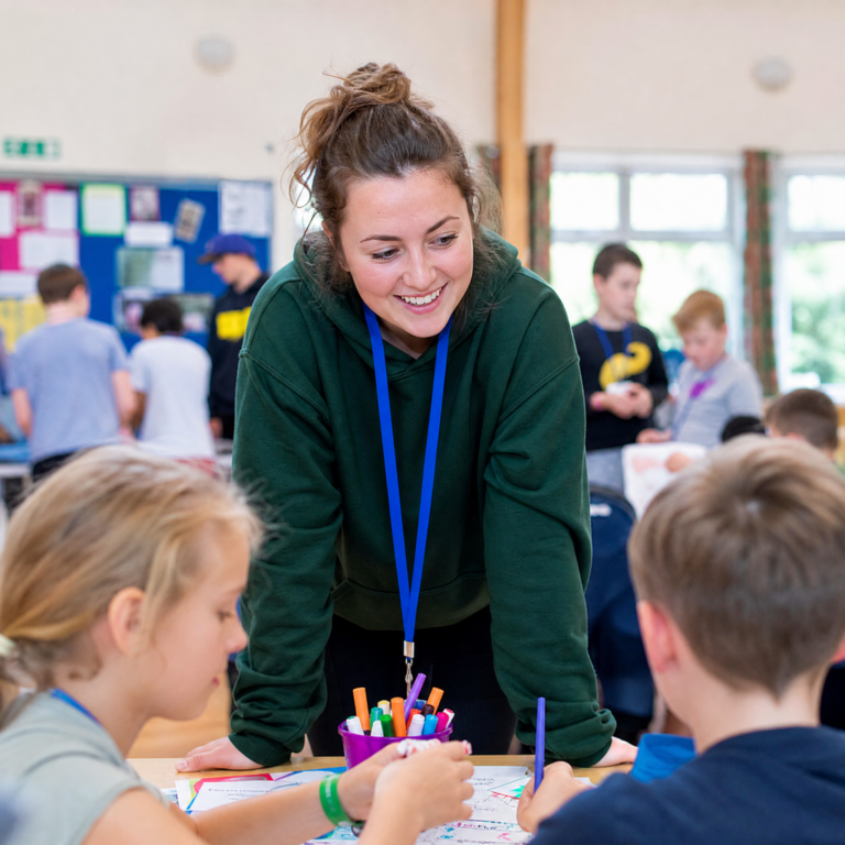 Activity leader supervising children doing crafts in a community hall out-of-school setting